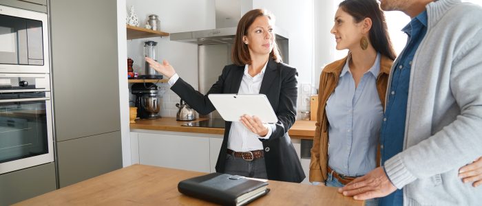 Maklerin zeigt jungem Paar eine Immobilie bei einem Besichtigungstermin