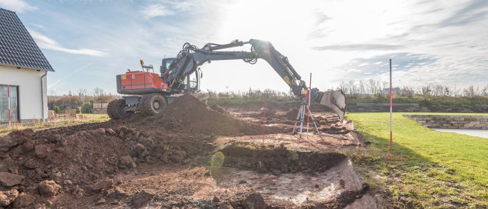 Bagger hebt Erde für die Erschließung eines Baugrundstücks