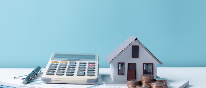 Taschenrechner und Modellhaus zur Berechnung von Kosten beim Hausverkauf