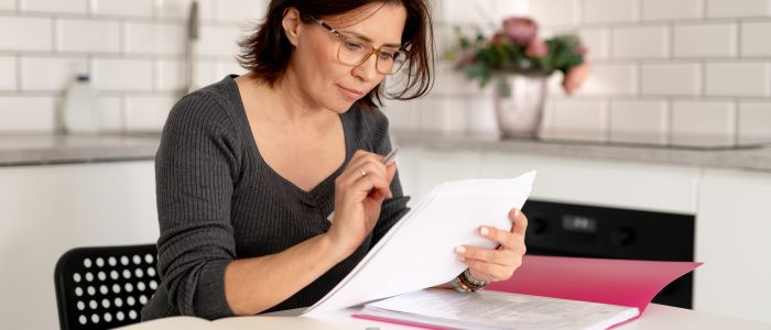 Frau am Küchentisch berechnet die Vorfälligkeitsentschädigung bei Hausverkauf